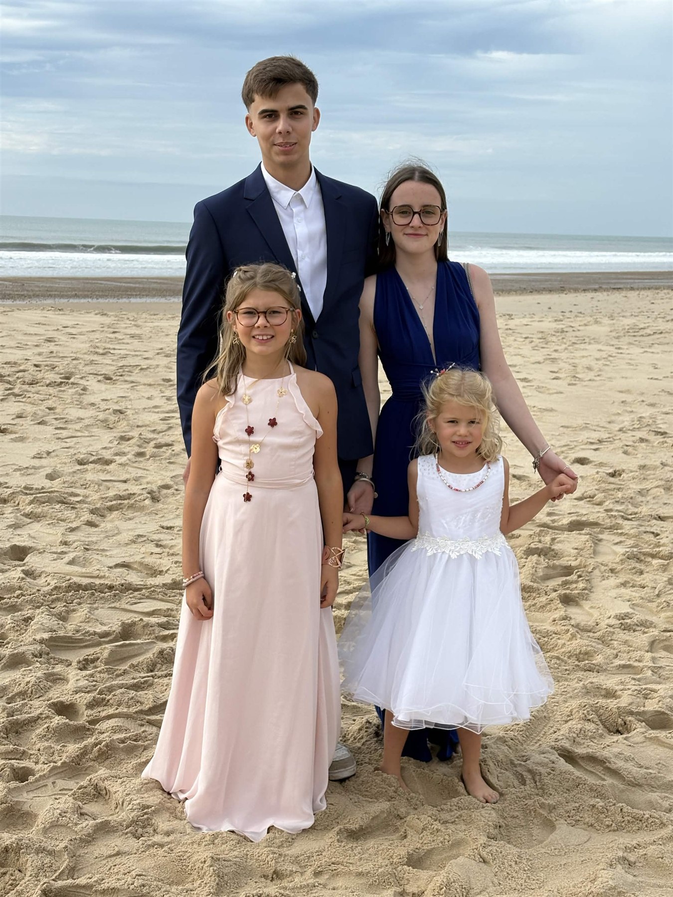 Vous posez à quatre au bord de la mer, habillés pour une belle occasion.